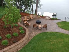 an outdoor patio with chairs and tables next to the water, surrounded by green grass