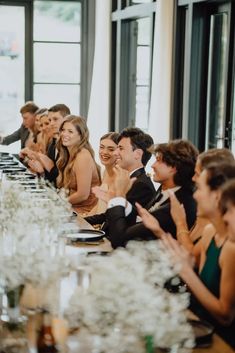 a group of people sitting at a long table with plates and glasses in front of them