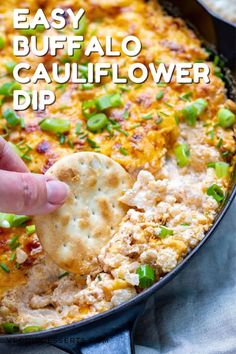 a hand dipping a cracker into a skillet filled with cauliflower dip