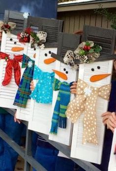 some people holding up snowmen made out of mailboxes with bows and scarves on them