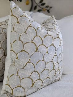 two white and gold pillows sitting on top of a bed next to eachother