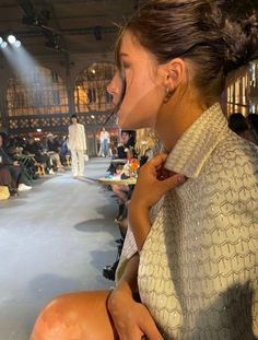 a woman sitting in front of a crowd at a fashion show