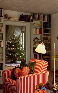 a red and white striped couch sitting in front of a book shelf filled with books