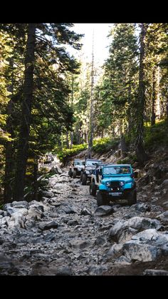 four jeeps driving down a rocky road in the woods