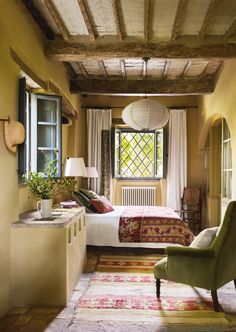 a bed room with a neatly made bed and a green chair next to a window