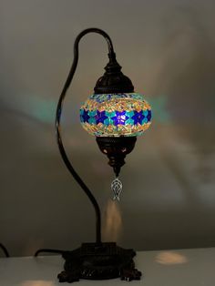 a lamp that is sitting on top of a white table with a blue and yellow glass shade