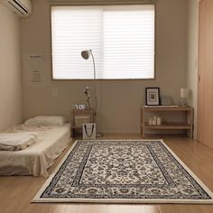 a bedroom with a bed, rug and window blinds in it's corner area