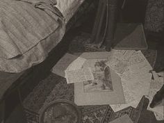 an old photo of a cat laying on the floor next to a bed with papers all over it