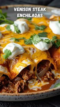 a close up of a plate of enchiladas with meat and sour cream