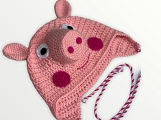 a pink crocheted pig hat with eyes and nose on it's side