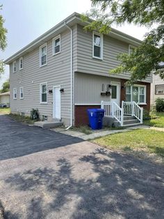 a two story house with a blue trash can in the driveway