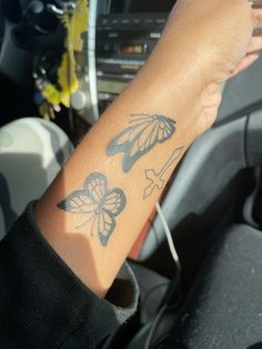 a woman's arm with two butterflies on it, and the wrist is in her car