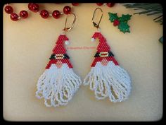 two red and white beaded earrings with santa claus's hat on them next to christmas decorations