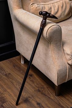 a large black cane sitting on top of a wooden floor next to a couch and chair