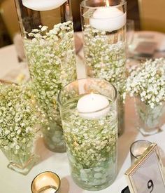 several vases with flowers and candles on a table