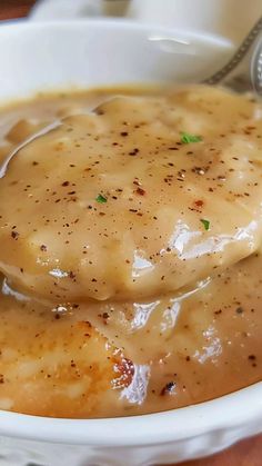 a white bowl filled with gravy on top of a wooden table