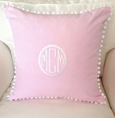 a pink and white pillow with pom - poms on the front, sitting on a chair