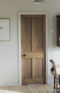 an empty room with a wooden door and chair next to the table in front of it