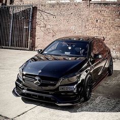 a black car parked in front of a brick wall