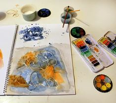 an artist's desk with paints, brushes and watercolors