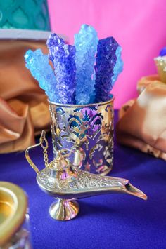 purple and blue flowers are in a silver vase on a table with other items around it