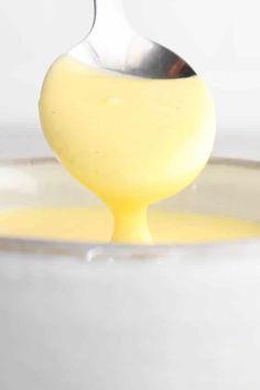 a spoon full of yellow liquid in a bowl