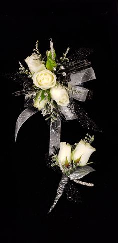 two white roses are tied together with silver ribbon and some other flowers is laying on the table