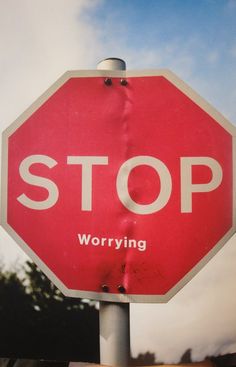 a red stop sign with the word worrying written on it in front of a cloudy sky