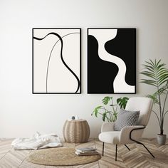 two black and white paintings hanging on the wall above a chair in a living room