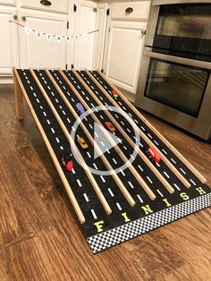 a toy track with cars on it in the middle of a kitchen