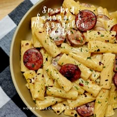 a bowl filled with pasta and sausages on top of a checkered table cloth