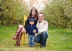 a man, woman and child posing for a photo in an apple orchard