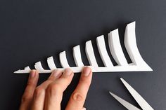 a person is cutting paper with scissors on a black surface next to some cut outs