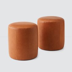 two brown leather stools sitting next to each other