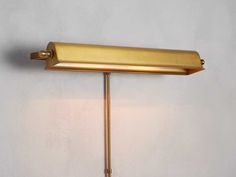 a wall mounted lamp with a white shade on it's side and a gold finish