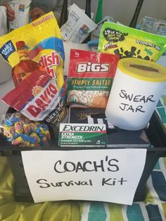 a basket filled with snacks on top of a bed next to a sign that says coach's survival kit