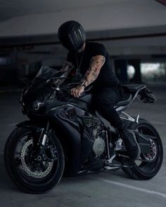 a man riding on the back of a black motorcycle in a parking lot at night