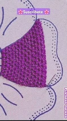 a purple crocheted bow tie sitting on top of a piece of cloth