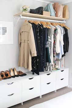 an organized closet with shoes, coats and handbags hanging on the rail above it