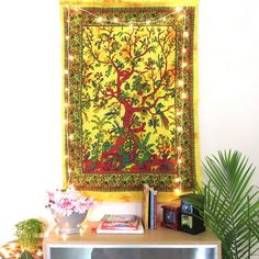 a wall hanging with a tree on it and some plants in the corner next to it