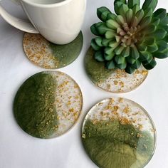 three green coasters sitting on top of a table next to a cup and plant