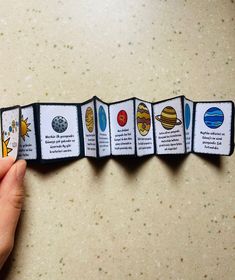 a hand holding an unopened card with pictures of different planets and sun on it