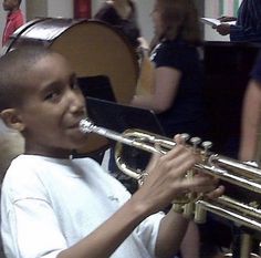 a young boy playing a trumpet in a room full of people