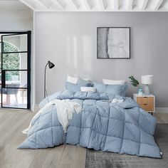 a bed with blue comforter and pillows in a room next to a door that leads to a patio