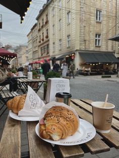 two croissants sitting on top of a white plate next to a cup of coffee