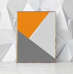 an orange, grey and white abstract painting in front of a wall with geometric shapes