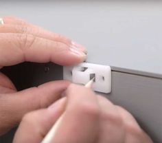 a person is fixing an electrical outlet on a wall with one hand and two fingers