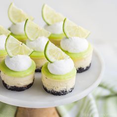 mini lime cheesecakes on a white plate with lime slices and marshmallows