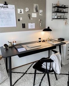 a black and white desk with a lamp on it next to a wall mounted poster