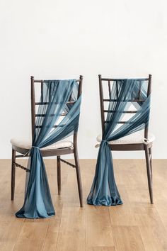 two chairs with blue draping on them sitting in front of a white wall